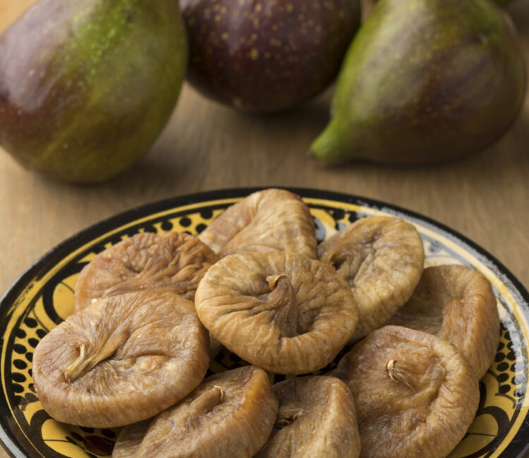 Dish with dried figs and ripe fresh ones on the background